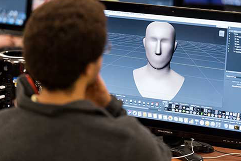 student looking at a computer screen with a 3d rendering of a head